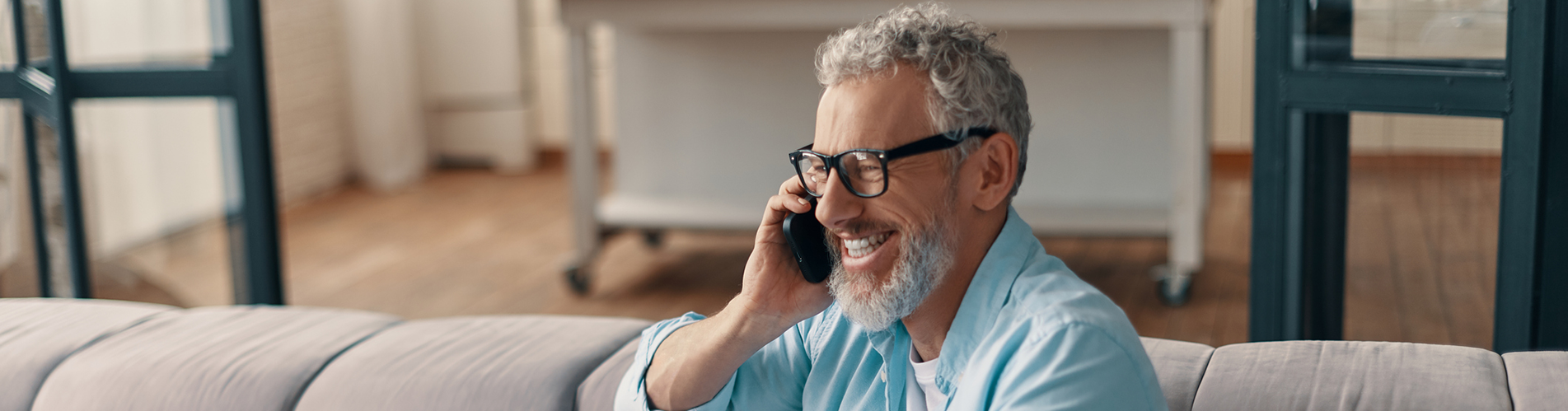 man sitting on his sofa, talking on a phone